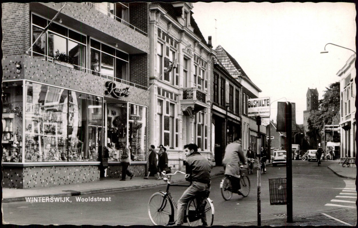 vergrößern: Bildseite historische Ansichtskarte von 1962: Wooldstraat Geschäfte & Bus-Haltestelle:: Winterswijk