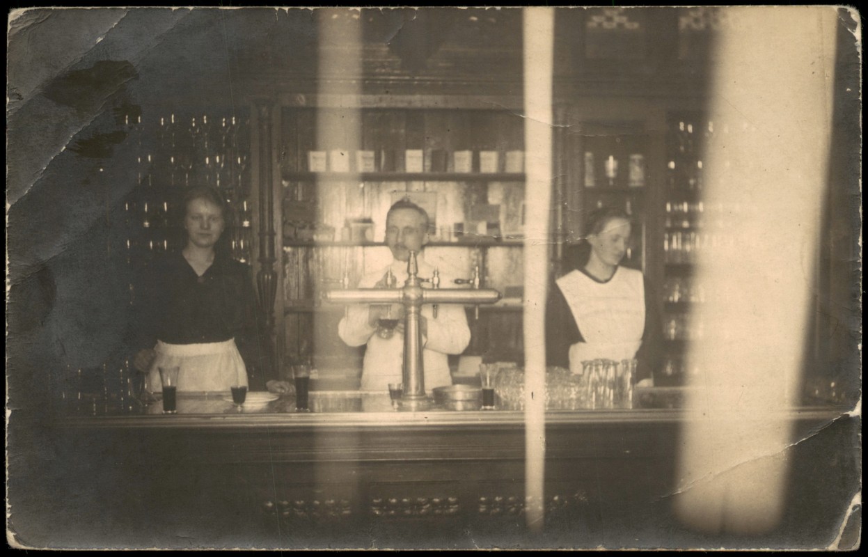 vergrößern: Bildseite historische Ansichtskarte von 1930: Gaststätte mit Personal am Tresen, Ausgeschänkte Getränke auf der Bar::
