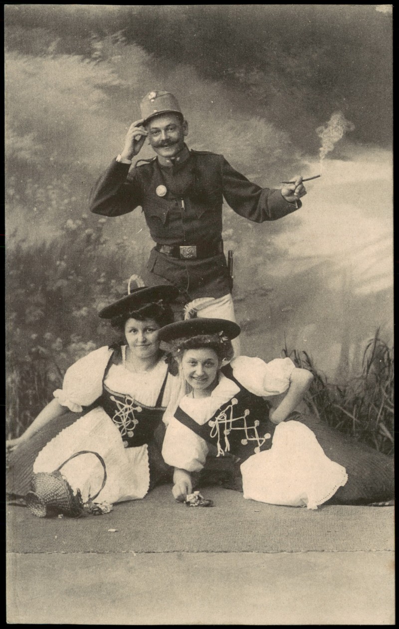 vergrößern: Bildseite historische Ansichtskarte von 1910: Künstlerkarte - Militär Soldat mit Zigarette vor zwei Frauen in Tracht::